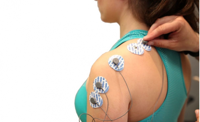 mujer con electrodos en hombro y espalda